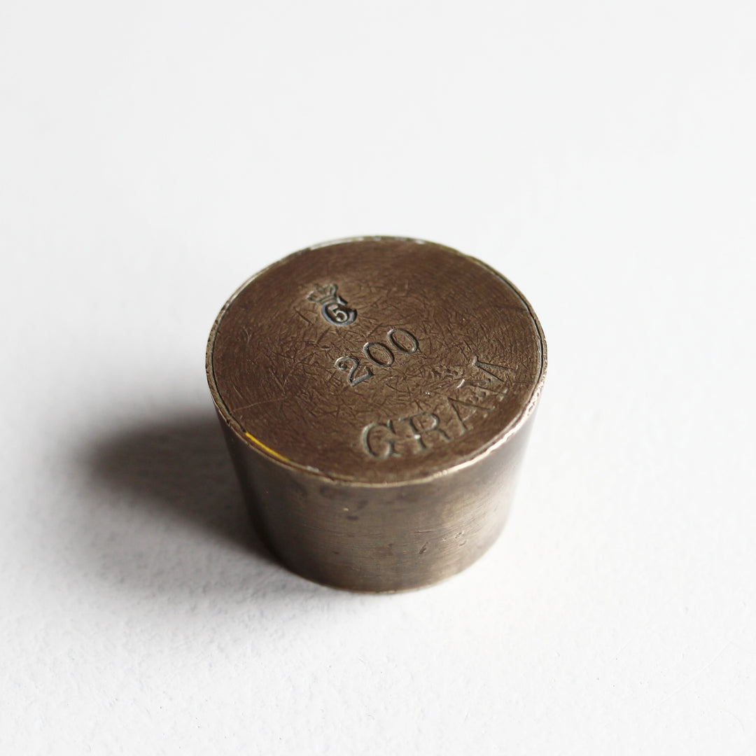 Alter zylindrischer Messing-Briefbeschwerer aus einem 200-Gramm-Handelsgewicht mit eingeprägter Gewichtsangabe und natürlicher Patina.