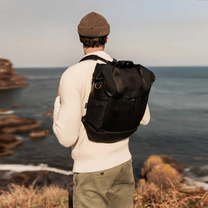 Chiloé Backpack Black getragen an der Küste mit Blick auf das Meer