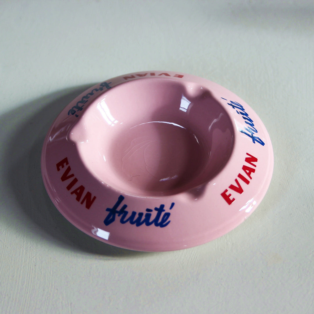 Rosafarbener Evian Fruité Keramik-Aschenbecher mit rotem Evian-Schriftzug, blauem Fruité-Logo und vier Zigarettenablagen.