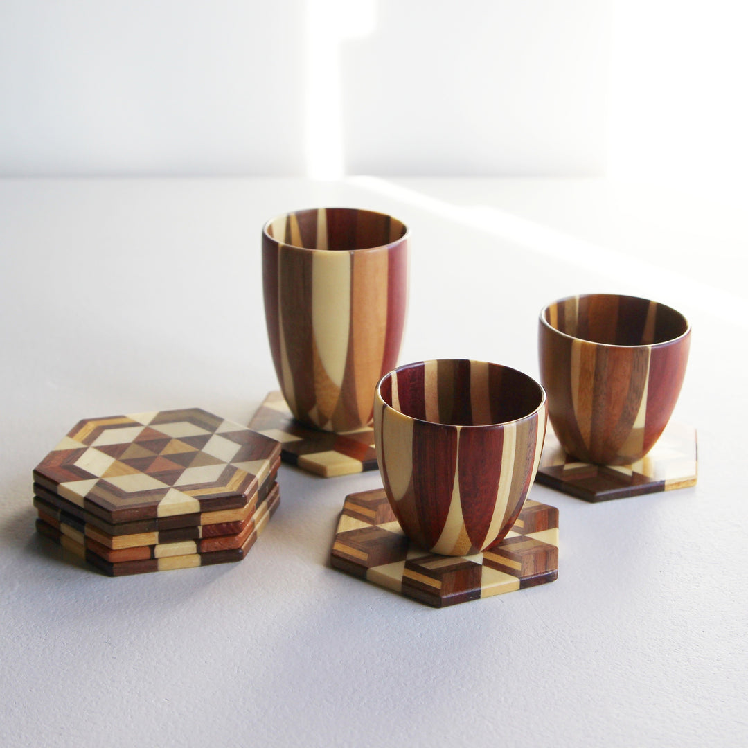 Japanisches Yosegi Holzbecher-Set mit drei unterschiedlich großen Bechern und acht sechseckigen Untersetzern aus mehrfarbigem Holzmosaik.