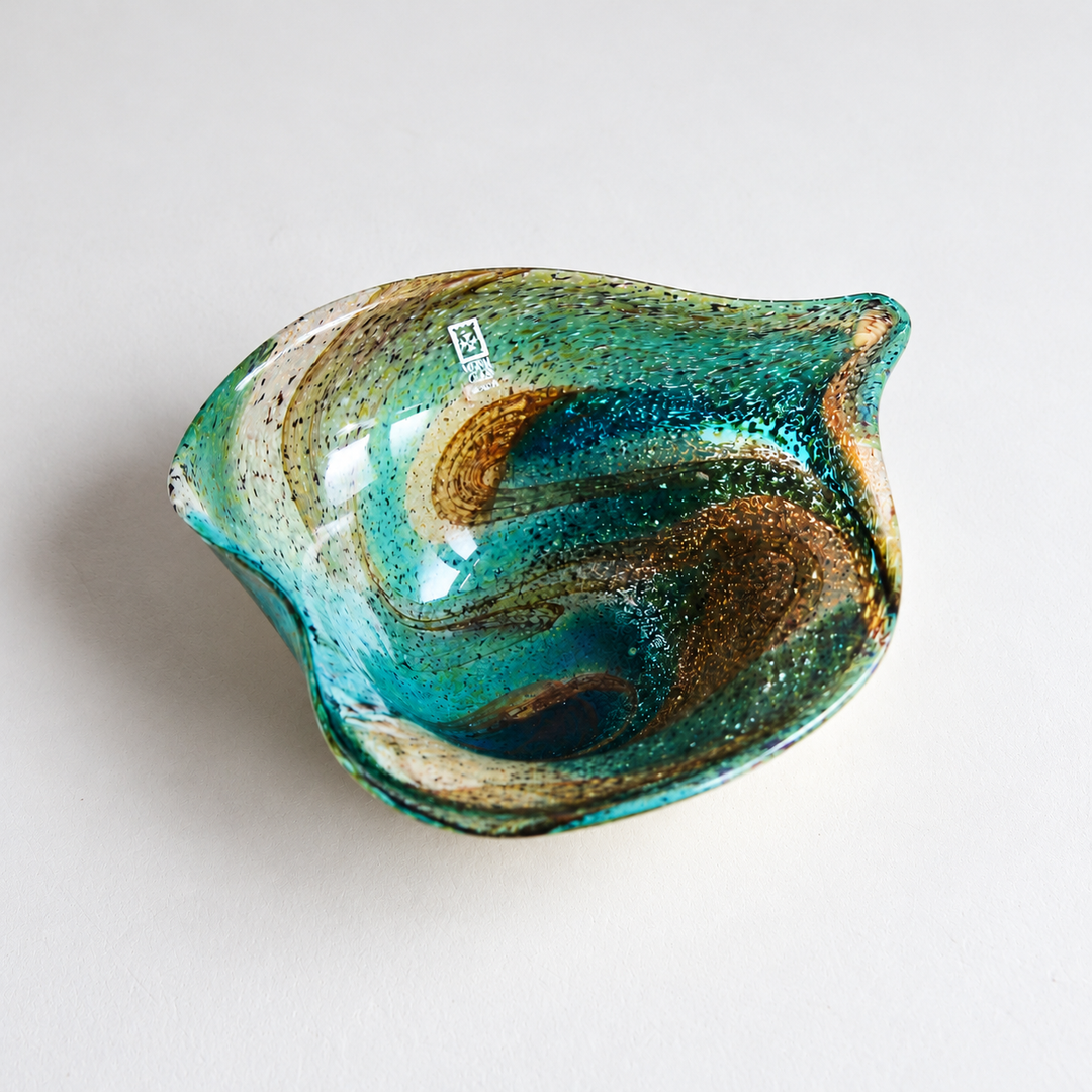 Signierte Mdina Glass Kunstglasschale aus Malta mit geschwungenem Rand und wirbelnden Farbverläufen in Türkis, Blau und Bernstein.