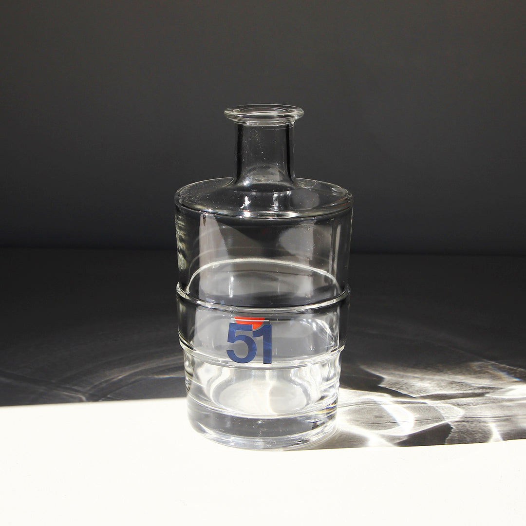 Runde Pastis 51 Wasserkaraffe aus klarem Glas mit blau-rotem 51-Logo, drei umlaufenden Ringen und schmalem Flaschenhals.