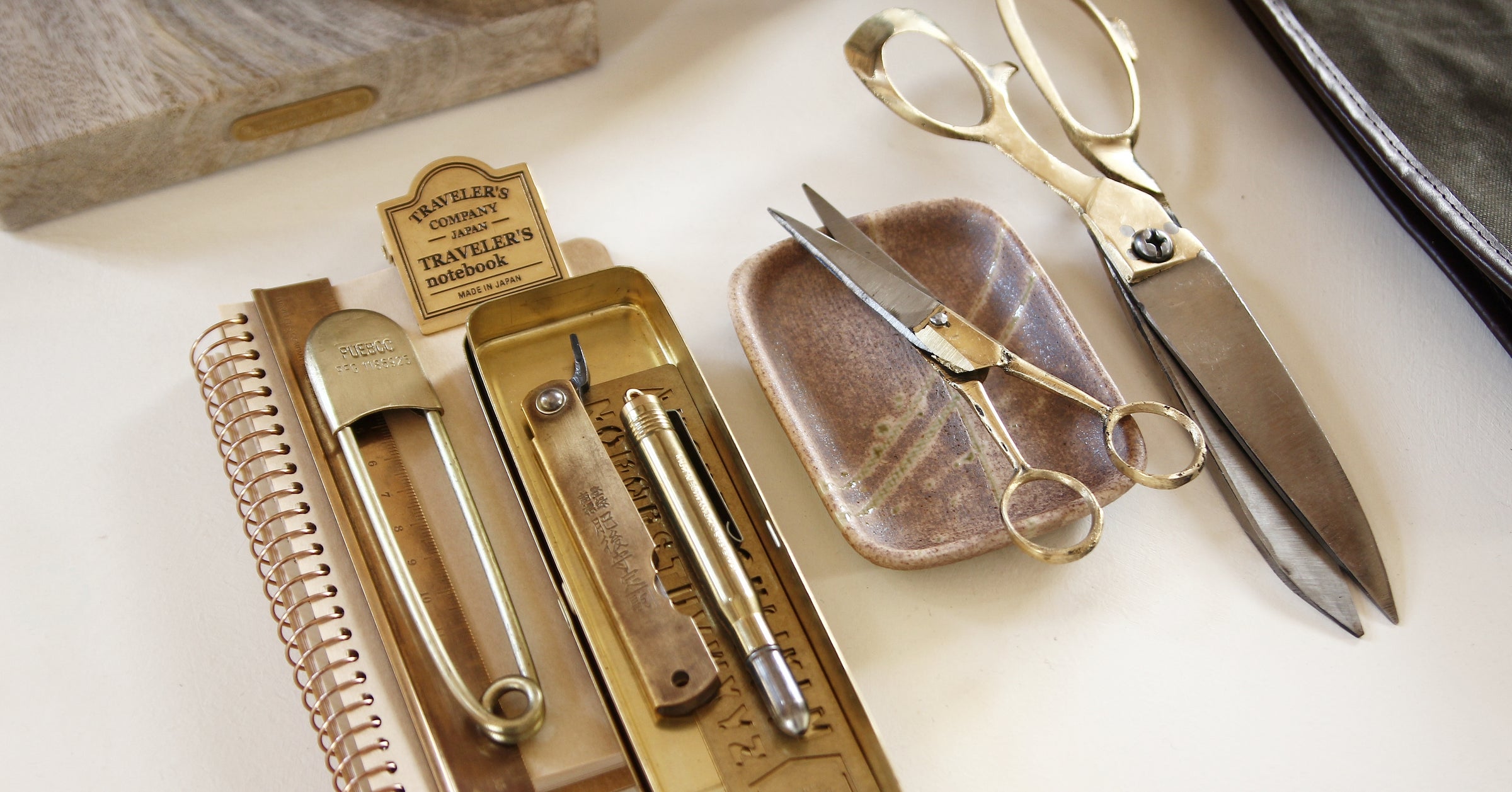 Collection of brass everyday objects with scissors and knife on ceramic tray
