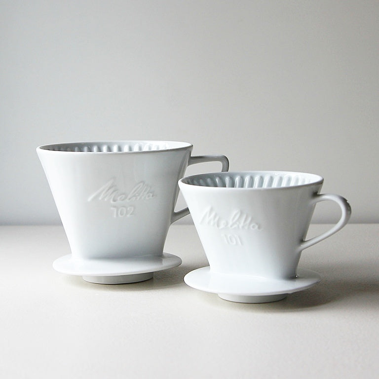 Vintage Melitta Kaffeefilter aus weißem Porzellan in den Größen 101 und 102 mit eingeprägtem Melitta-Schriftzug.