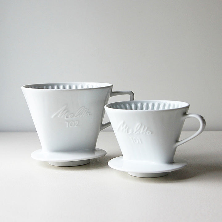 Vintage Melitta Kaffeefilter aus weißem Porzellan in den Größen 101 und 102 mit eingeprägtem Melitta-Schriftzug.