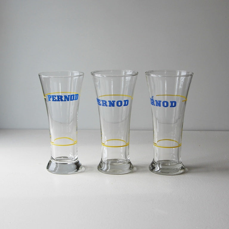 Drei originale Vintage Pernod Pastisgläser mit blauem Logo und gelben Eichringen aus französischer Bistrokultur.