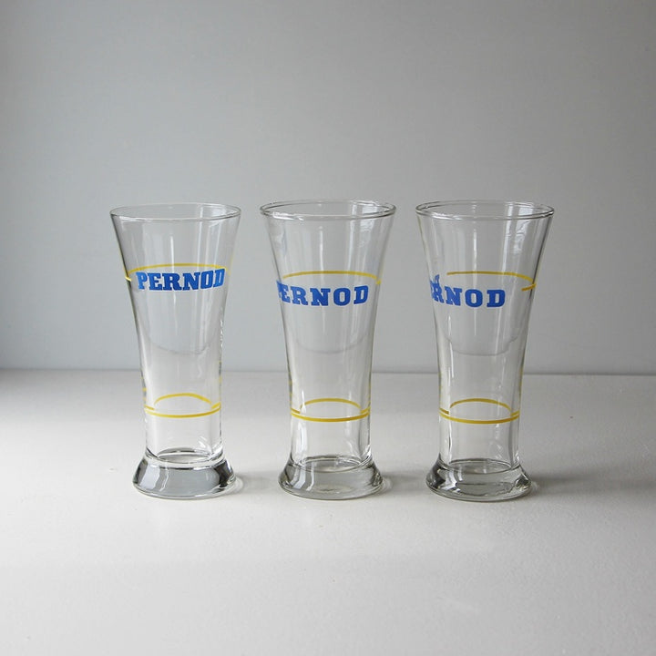 Drei originale Vintage Pernod Pastisgläser mit blauem Logo und gelben Eichringen aus französischer Bistrokultur.